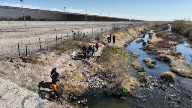 EL PASO, TEXAS - FEBRUARY 1: In this aerial view, immigrant groups cross water and barbed wire and walk to the US/Mexico border despite extra security measures on February 1, 2024 in El Paso, Texas.