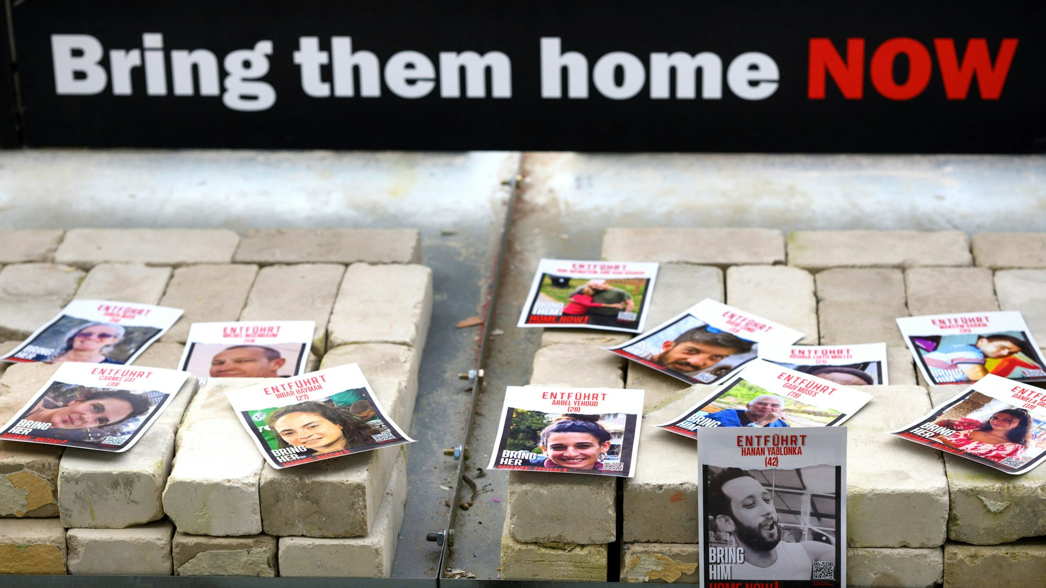 08 April 2024, Berlin: Photos of Hamas hostages lie in front of the Paul Löbe House at the German Bundestag during a protest action by Israeli relatives of Hamas hostages. With a symbolic hourglass filled with red sand and the words "Time is running out" and "Bring them home now", they are campaigning for the release of the hostages taken to Gaza by Hamas terrorists.