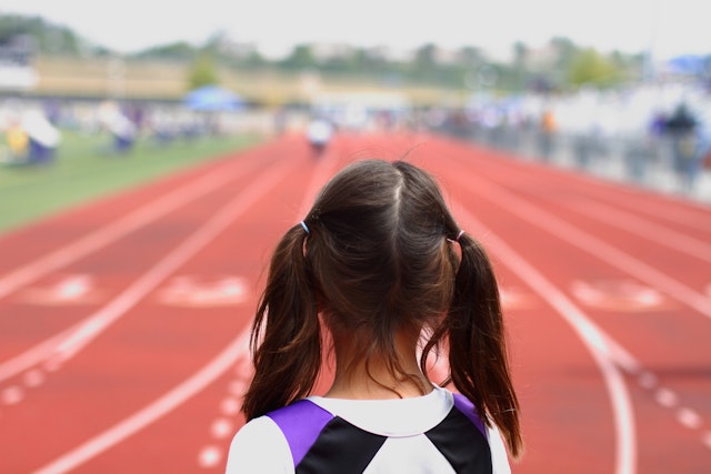 "A picture of a youth girl at the starting line, about to compete in a track &amp; field event."