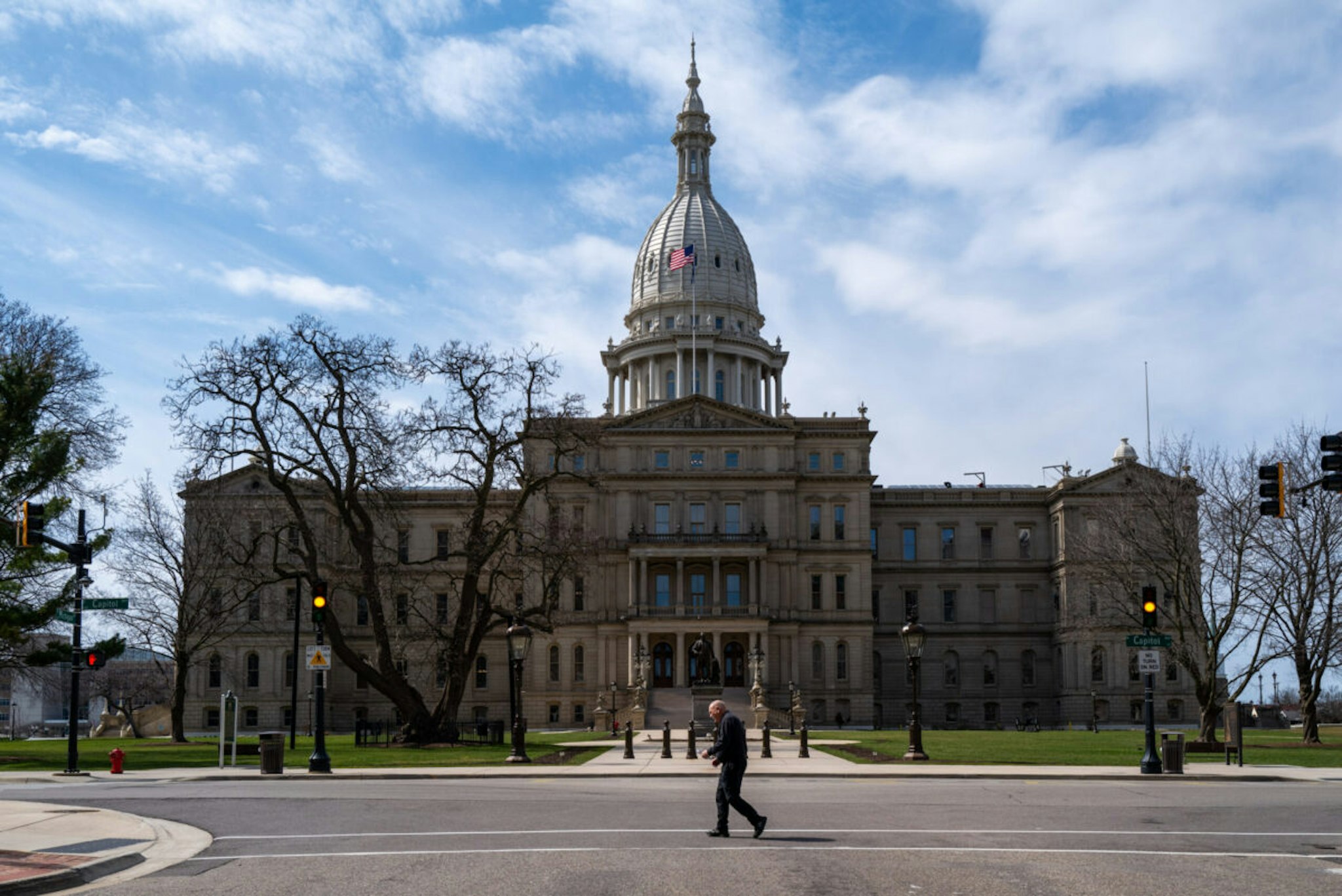 LANSING, MICHIGAN - APRIL 01: A man crosses the street in front of the state capital building in downtown Lansing on April 01, 2024 in Lansing, Michigan. According to recent state employment data projections, the number of jobs in Michigan is not expected grow over the next seven years as the state struggles with population growth and an auto industry facing challenges. In population growth, Michigan ranks 49th in the country ahead of only West Virginia.