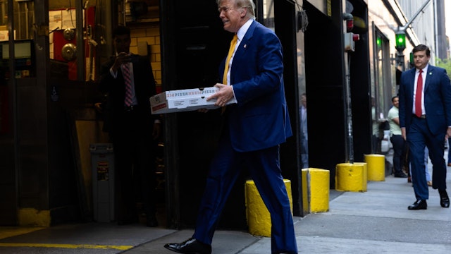 NEW YORK, NEW YORK - MAY 02: Republican presidential candidate former U.S. President Donald Trump carries boxes of pizza for the FDNY Engine 2, Battalion 8 firehouse on May 02, 2024 in New York City. Trump delivered pizza to a firehouse after a court appearance in his hush money trial, which started with a hearing where prosecutors argued that Judge Juan Merchan should find Trump in criminal contempt again for violating a gag order. Earlier this week, Trump was found in contempt for nine violations of his April 1 order prohibiting criticism of witnesses and jurors. (Photo by Michael M. Santiago/Getty Images)
