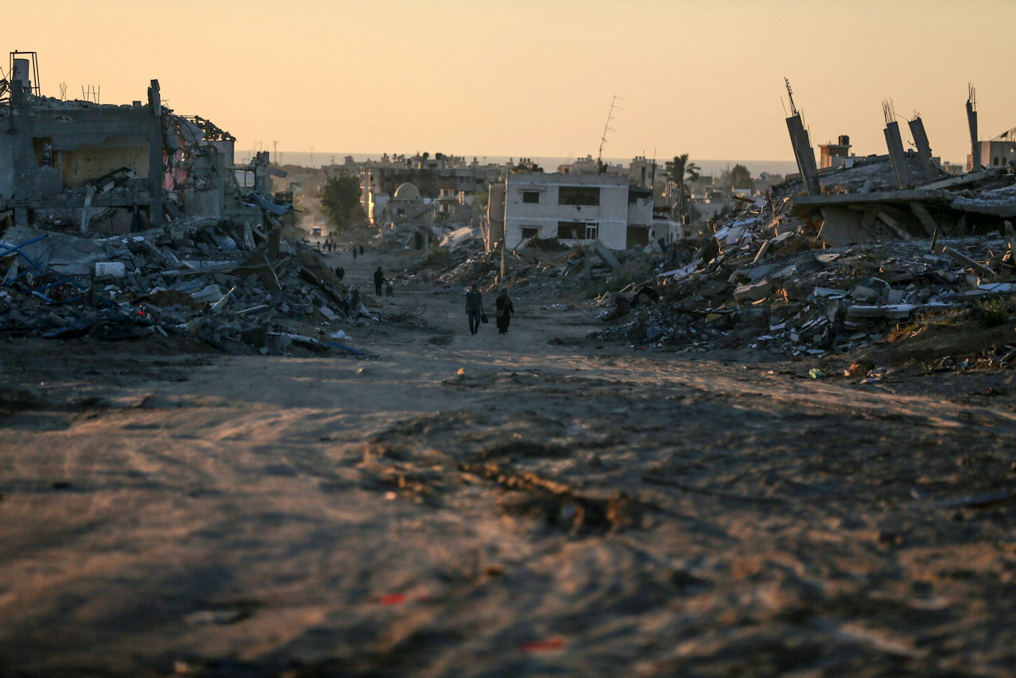 Palestinians are walking between damaged buildings in Khan Yunis in the southern Gaza Strip on May 7, 2024, amid the ongoing conflict between Israel and the Hamas movement.