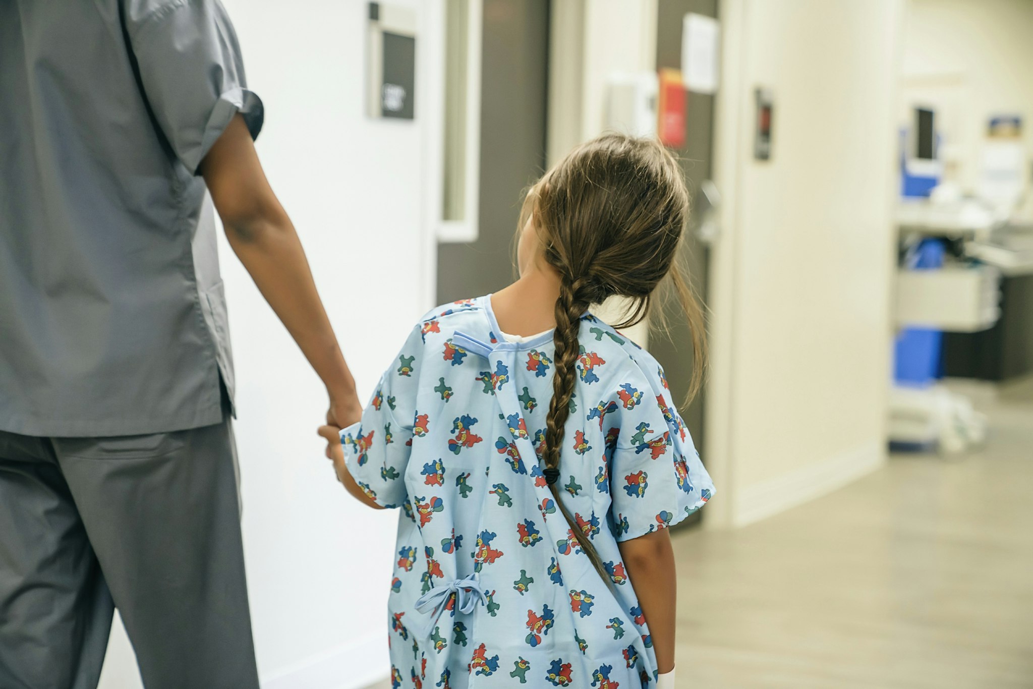 Nurse holding hands with girl in hospital
