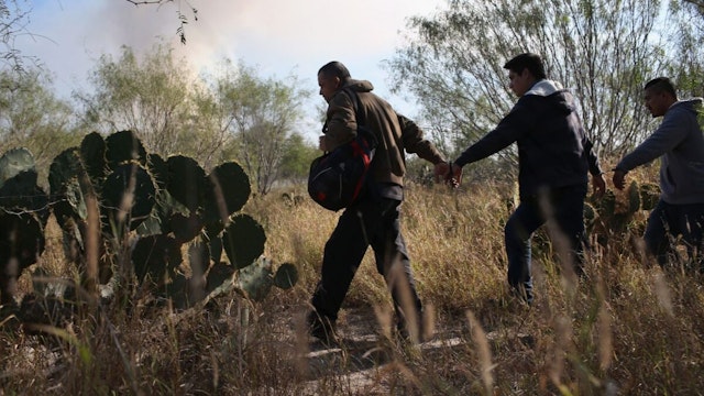 RIO GRANDE CITY, TX - DECEMBER 07: Immigrants walk handcuffed after illegally crossing the U.S.-Mexico border and being caught by the U.S. Border Patrol on December 7, 2015 near Rio Grande City, Texas.