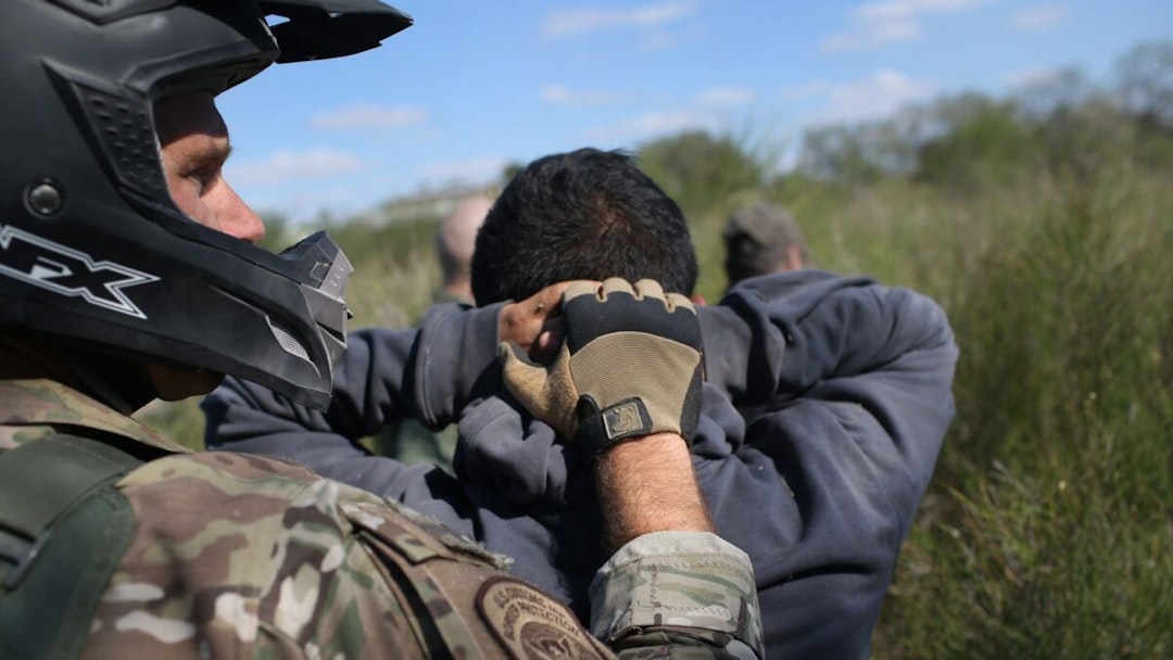 RIO GRANDE CITY, TX - DECEMBER 07: A U.S. Border Patrol agent leads undocumented immigrants through the brush after capturing them near the U.S.-Mexico border on December 7, 2015 near Rio Grande City, Texas.