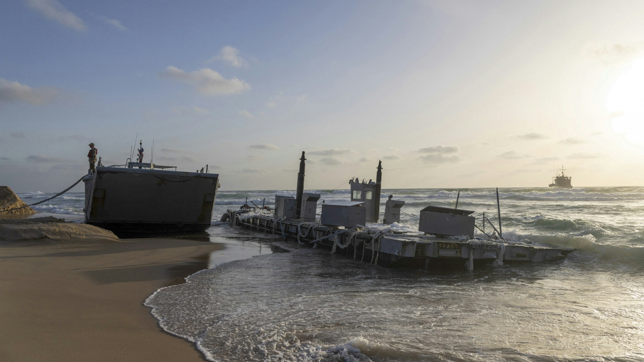 A US soldier stands on a US military vessel that ran aground at a beach in the Israeli coastal city of Ashdod on May 25, 2024. The US military said four of its vessels, supporting a temporary pier built to deliver aid to Gaza by sea, had run aground in heavy seas.