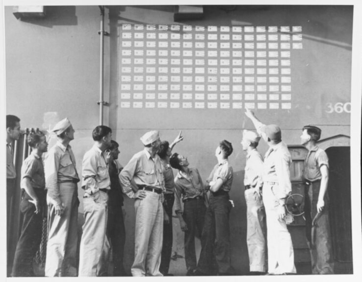 USS LEXINGTON (CV-16). Officers and crewman admire Japanese flags painted on the carrier's island, commemorating 143 