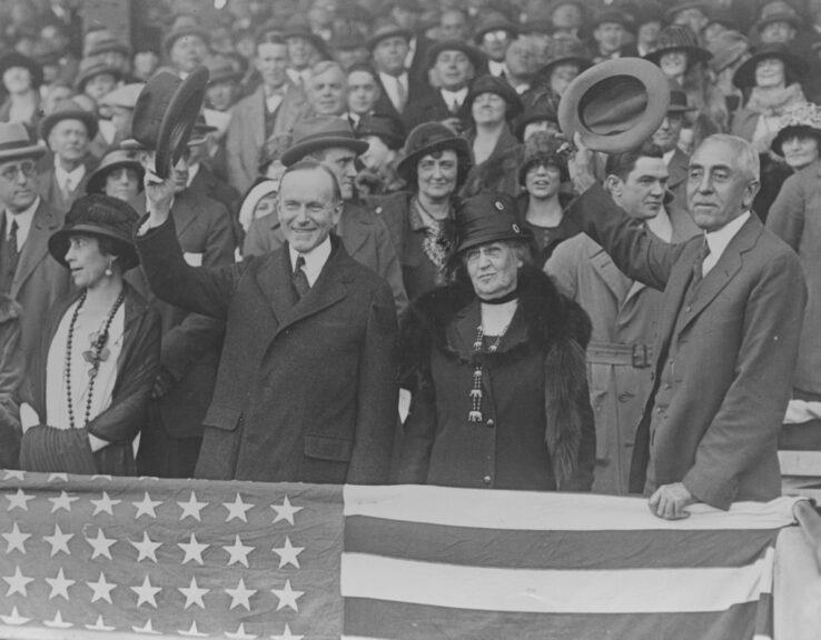 Grace Coolidge (1879-1957), First Lady of the United States, United States President Calvin Coolidge (1872-1933), the wife of Coolidge's friend Frank Stearns, and C. Bascom Slemp (1870-1943), Secretary to the President, sitting in their box at the sixth game of the World Series in Washington, D.C., USA, circa 1925. Coolidge and Slemp are pictured waving their hats, cheering on their team, from the box, draped in a United States flag. (Photo by FPG/Getty Images)