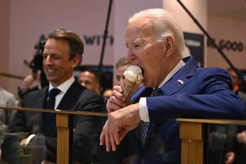 TOPSHOT - US President Joe Biden (R), flanked by host Seth Meyers (L), eats an ice cream cone at Van Leeuwen Ice Cream after taping an episode of "Late Night with Seth Meyers" in New York City on February 26, 2024. (Photo by Jim WATSON / AFP) (Photo by JIM WATSON/AFP via Getty Images)