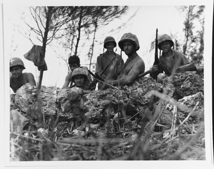 Saipan Operation, June 1944. Marines pose in a foxhole near the Saipan front lines, 1 July 1944. Photo by USS INDIANAPOLIS. Note tattoo on man 2nd from right. National Archives. Naval History and Heritage Command.