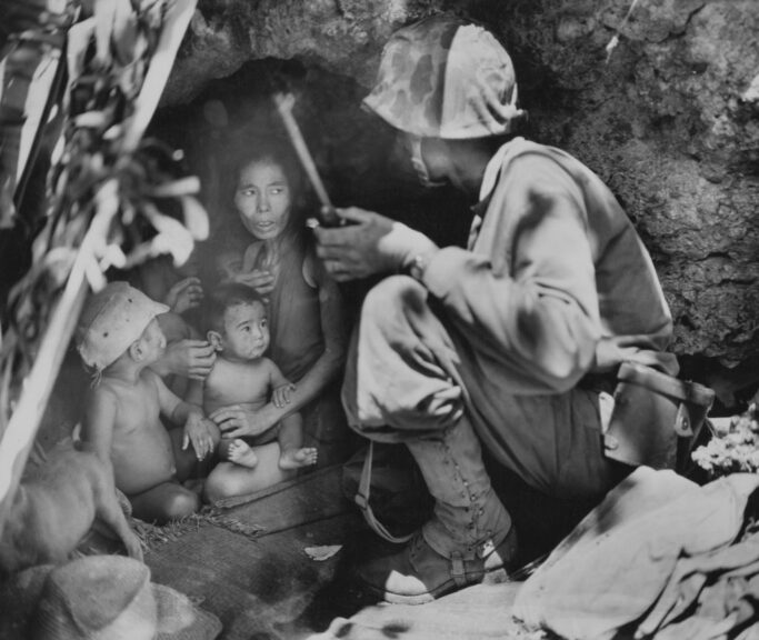 First Lieutenant Robert B Sheeks, a combat Intelligence and Japanese Language Officer with the 2nd Marine Division of the United States Marine Corps talks with a Chamorro woman and her children into leaving their hillside cave refuge following the invasion of the island by US forces during the Mariana and Palau Islands campaign (Operation Forager) on 21st June 1944 at Saipan island in the Northern Mariana Islands. US Marine Corps Official Photo. (Photo by Angus Robertson/FPG/Archive Photos/Getty Images).