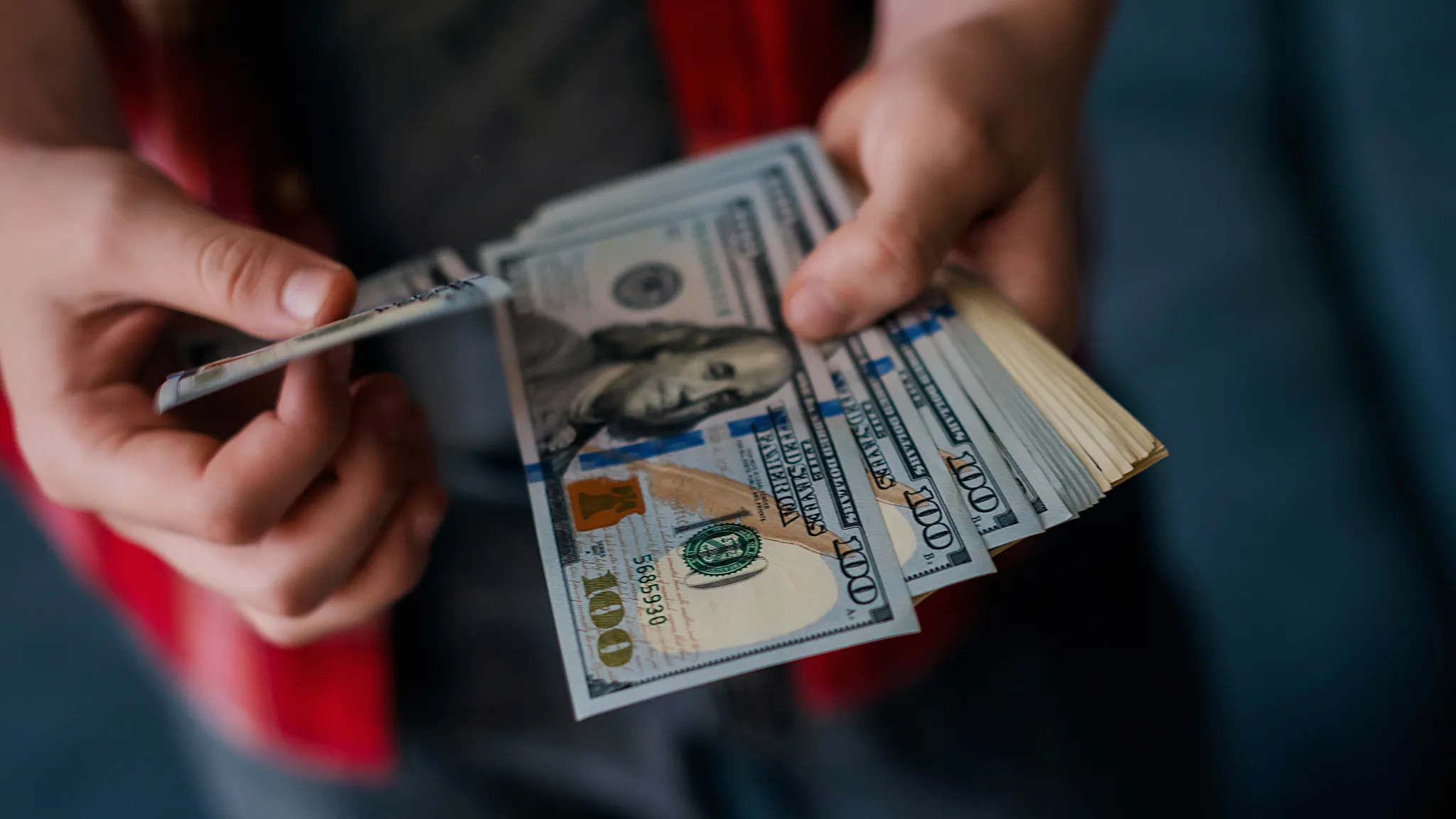 man holding US one hundred Dollar bills