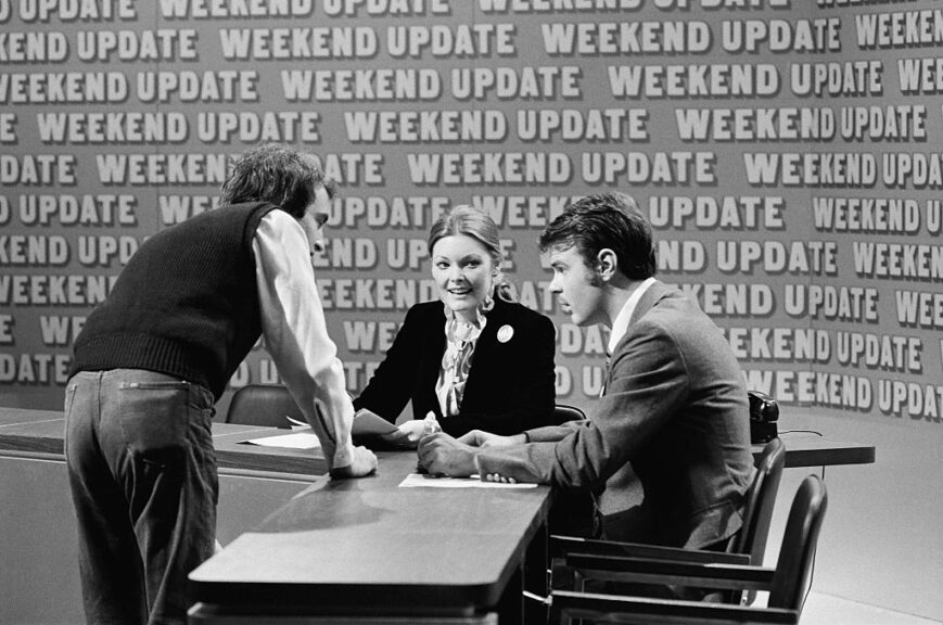 SATURDAY NIGHT LIVE -- Episode 3 -- Pictured: (l-r) Lorne Michaels, Jane Curtin, Dan Aykroyd during the 'Weekend Update' skit on October 15, 1977 -- (Photo by: NBCU Photo Bank/NBCUniversal via Getty Images via Getty Images)