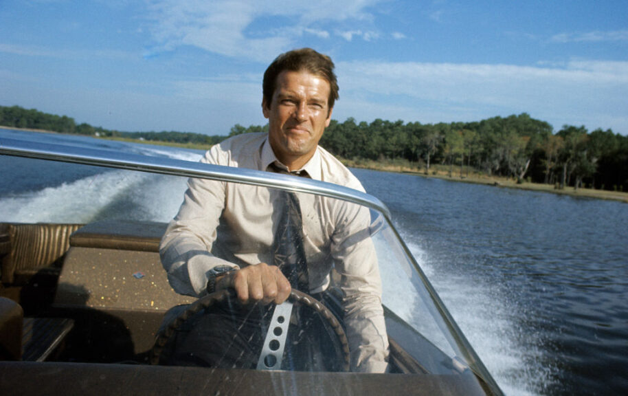 KINGSTON, JAMAICA - MARCH 1: Roger Moore poses driving a speedboat during the filming of James Bond film 'Live And Let Die' on March 1, 1973 in Kingston, Jamaica (Photo by Anwar Hussein/Getty Images)