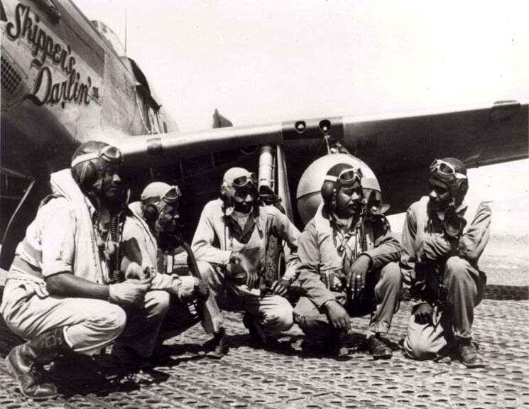 Tuskegee AirmenAugust 1944 - Fliers of a P-51 Mustang Group of the 15th Air Force in Italy shoot the breeze in the shadow of one of the Mustangs they fly. Tuskegee airmen, pilots of a P-51 Mustang Group of the 15th Air Force in Italy, shoot the breeze in the shadow of one of the Mustangs they fly, August 1944. They are, from left to right, Lt. Dempsey W. Morgan, Jr., Lt. Carroll S. Woods, Lt. Robert H. Nelson, Jr., Captain Andrew D. Turner, and Lt. Clarence P. Lester. (Photo by PhotoQuest/Getty Images)