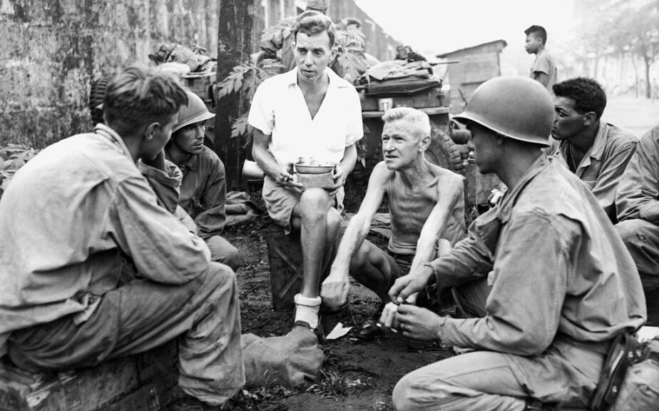 American soldiers who were part of the liberation of the Japanese Bilibid POW camp stop to talk with two internees who had been in the prison camp for two years, Manila, Philippines, February 11, 1945. (Photo by Underwood Archives/Getty Images)