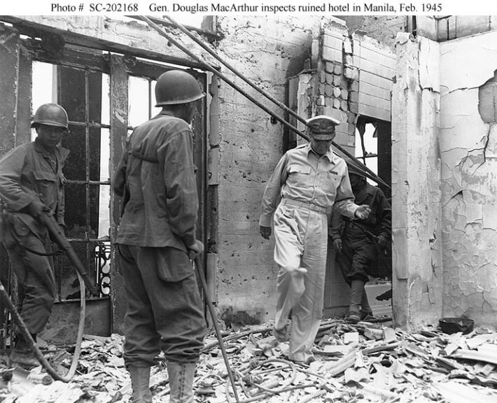 General MacArthur visits the ruins of the Manila hotel that was his pre-war home on Luzon, 23 February 1945. He is accompanied by Colonel James Corbett and two infantrymen, one armed with an M1 rifle. Photograph from the Army Signal Corps Collection in the U.S. National Archives. Naval History and Heritage Command.