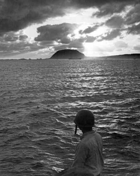 A rear view of an American military officer looking out over the Pacific Ocean, naval vessels in silhouette on the horizon, during the Battle of Iwo Jima, Second World War, with Mount Surabuchi rising in the distance on Iwo Jima, Japan, 1945. Fought from 19th February to 26th March 1945, the Battle of Iwo Jima saw the US Marine Corps and US Navy capture the island of Iwo Jima from Imperial Japan. (Photo by Fritz Olson/FPG/Archive Photos/Getty Images)