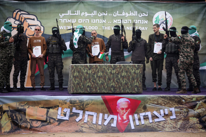 Palestinian Hamas fighters escort Israeli hostages before handing them over to a Red Cross team in Deir el-Balah, central Gaza, on February 8, 2025, as part of the fifth hostage-prisoner exchange of a fragile ceasefire. The swap comes after US President Donald Trump proposes clearing out the Gaza Strip of its inhabitants and for the United States to take over the Palestinian territory--a plan that sparks global uproar and is rejected by Hamas. (Photo by Majdi Fathi/NurPhoto via Getty Images)