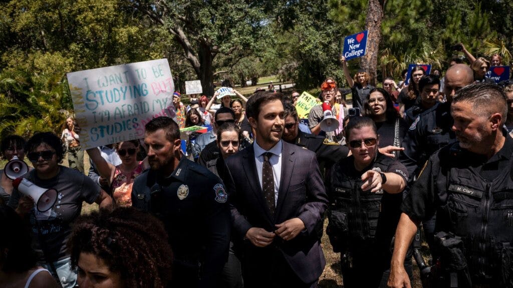 Christopher Rufo, a conservative activist and New College of Florida trustee, walks through protestors on his way out of a bill signing event featuring Florida Governor Ron DeSantis, who signed three education bills on the campus of New College of Florida in Sarasota, Fla. on Monday, May 15, 2023.