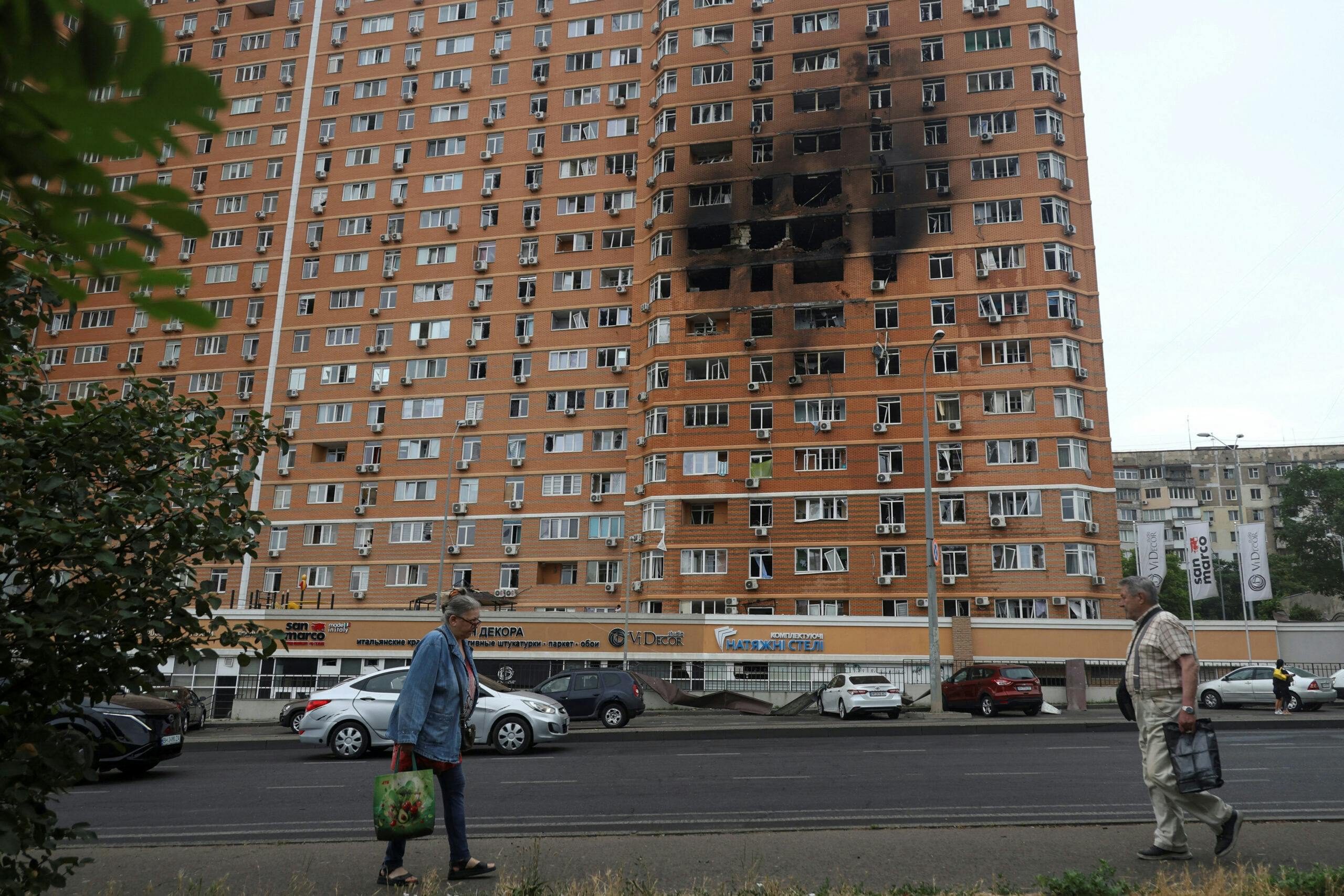 Residents walk in front of an apartment building hit by a Russian drone strike, amid Russia's attack on Ukraine, in Odesa, Ukraine June 28, 2025.