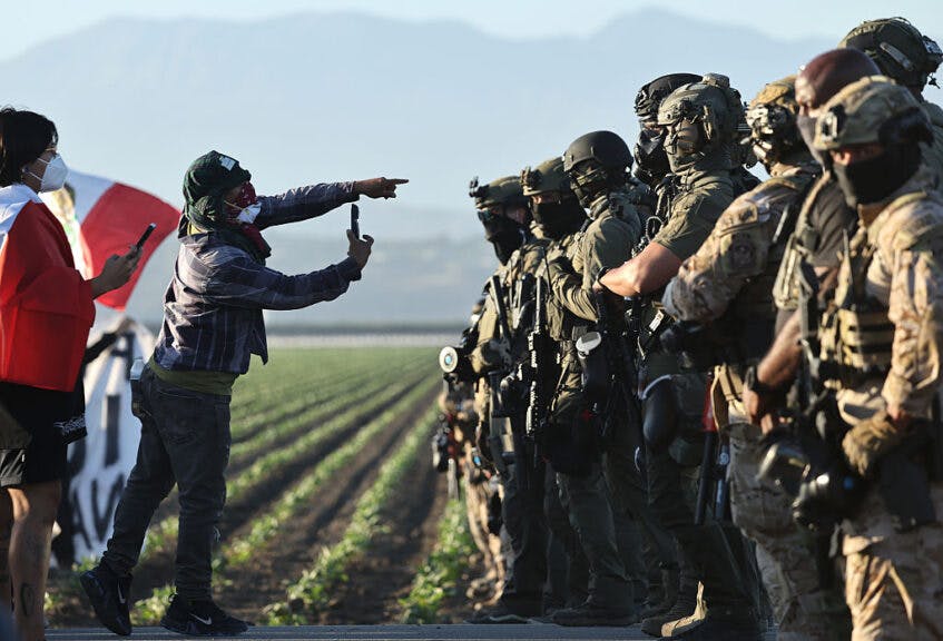 CAMARILLO, CALIFORNIA - JULY 10: Federal agents block people protesting an ICE immigration raid at a nearby cannabis farm on July 10, 2025 near Camarillo, California. Protestors stood off with federal agents for hours outside the farm in the farmworker community in Ventura County. A Los Angeles federal judge is set to rule Friday on a temporary restraining order which would restrict area immigration enforcement operations. (Photo by Mario Tama/Getty Images)