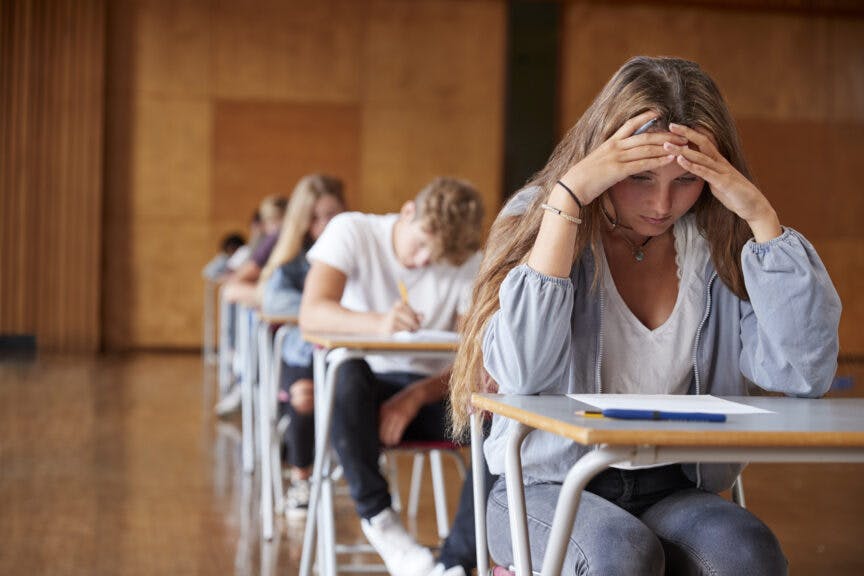 monkeybusinessimages. Getty Images. Anxious Teenage Student Sitting Examination In School Hall.
