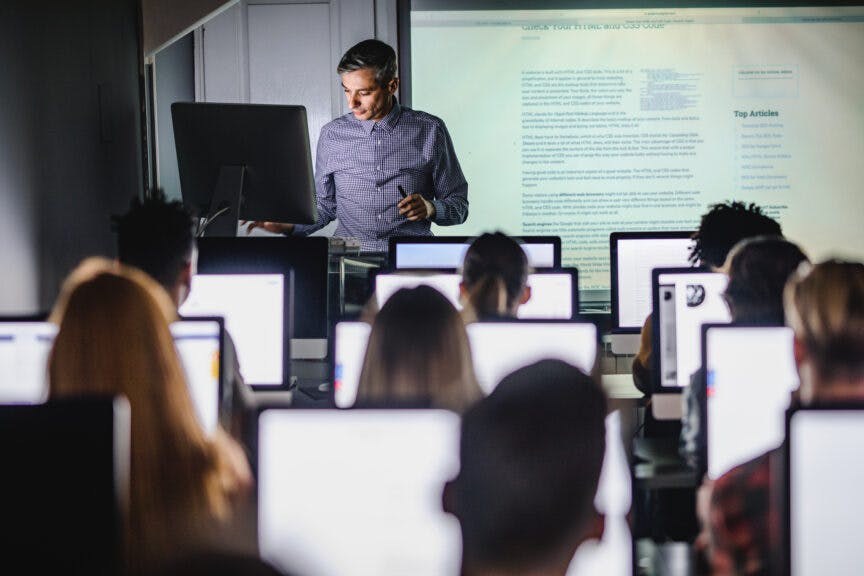 skynesher. Getty Images. Male teacher giving a lecture from desktop PC during a class at computer lab.