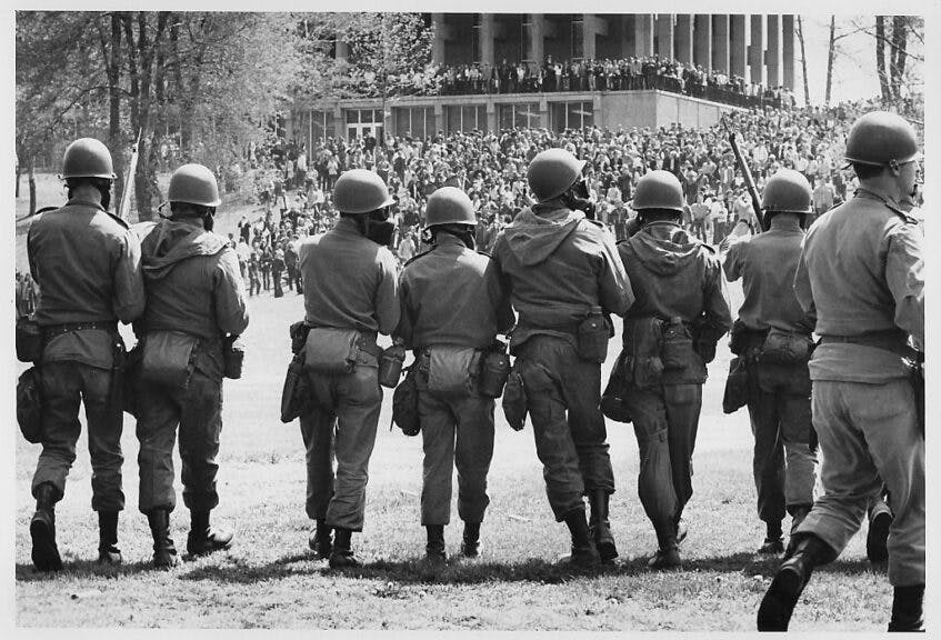 View, from behind, of members of the Ohio National Guard, with gas masks and fixed bayonettes, as they advance towards Blanket Hill to disperse antiwar demonstrators and students at Kent State University, Kent, Ohio, May 4, 1970. Four protestors were eventually shot and killed (and nine injured) when troops began to fire their weapons into the crowd. (Photo by Howard Ruffner/Getty Images)