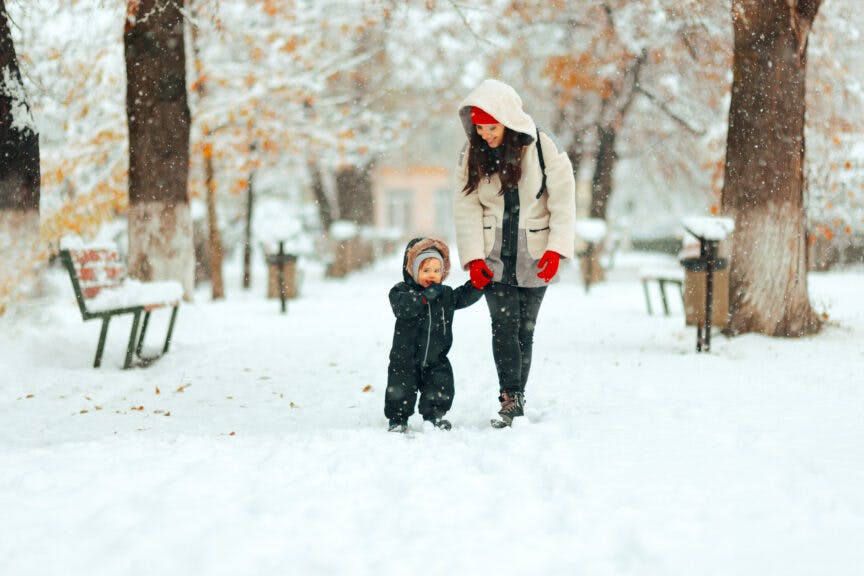 nicoletaionescu. Getty Images. Mother and child having fun walking outdoors in winter season