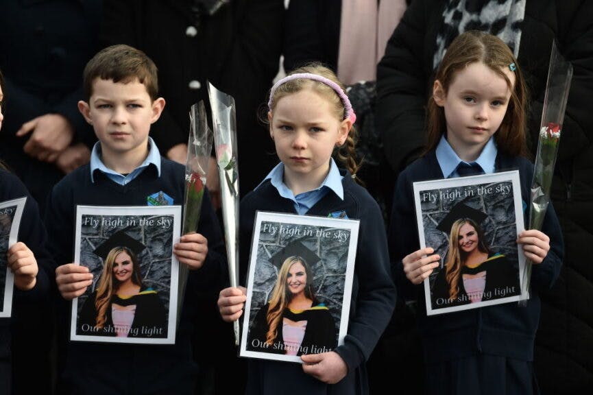 TULLAMORE, IRELAND - JANUARY 18: Pupils from Ashling Murphy's class hold photographs of her and red roses ahead of her funeral at St. Brigid’s Church, County Offaly on January 18, 2022 in Tullamore, Ireland. The murder of the beloved 23 year old school teacher has caused widespread anger and shock in Ireland, with tens of thousands of people attending vigils in recent days. (Photo by Charles McQuillan/Getty Images)