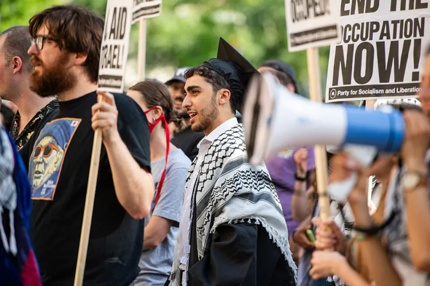 TOPSHOT - Pro-Palestinian protesters, some wearing cap and gown, hold signs and chant at a rally in front of the Massachusetts Institute of Technology (MIT) in Cambridge, Massachusetts, on May 28, 2024. (Photo by Joseph Prezioso / AFP) (Photo by JOSEPH PREZIOSO/AFP via Getty Images)