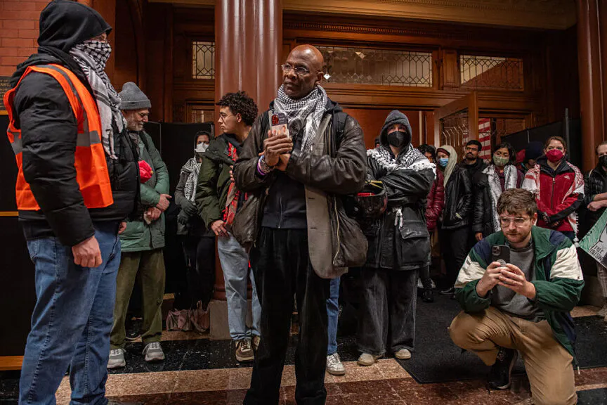 Michel DeGraff a former professor of linguistics and now faculty at large of the Massachusetts Institute of Technology (MIT) attends a protest at city hall in Cambridge, Massachusetts on December 9, 2024. The protest calls for the city to intervene and take action against MIT for its role in the Israeli and Palestinian conflict and for MIT to loose its non profit status. (Photo by Joseph Prezioso / AFP) (Photo by JOSEPH PREZIOSO/AFP via Getty Images)