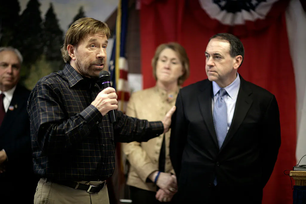 Republican presidential candidate Mike Huckabee listens as actor Chuck Norris speaks, during a visit the New Hampshire Veteran's Home in Tilton. Republican presidential candidate Mike Huckabee and actor Chuck Norris visit the N.H. Veteran's Home in Tilton. Norris accompanied Mike Huckabee as Huckabee campaigned in New Hampshire. | Location: Tilton, New Hampshire, USA.