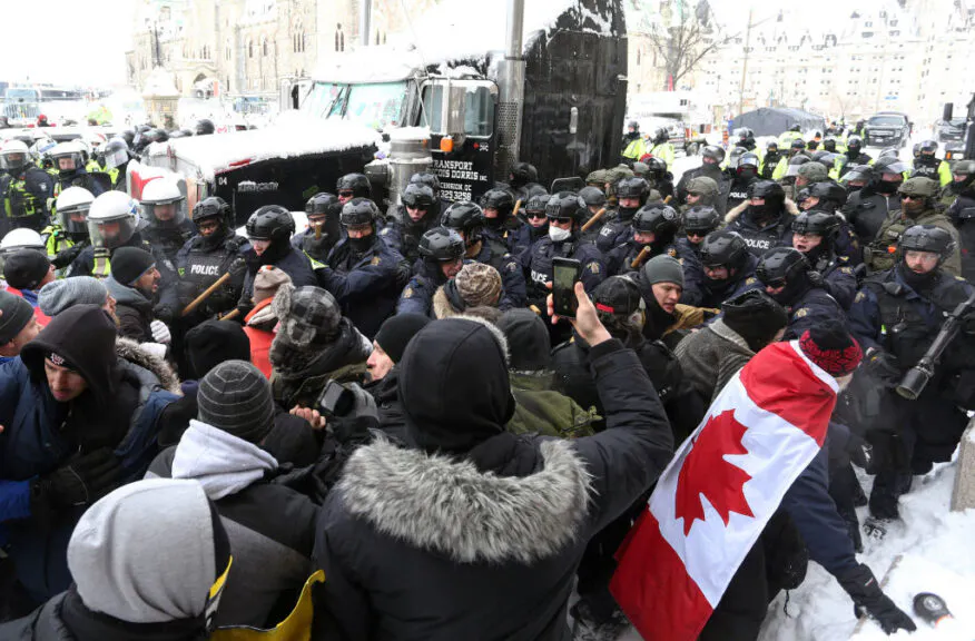 A line of police push protesters back on February 19, 2022 in Ottawa, Canada. - Police in Canada deployed to dislodge the final truckers and protesters from downtown Ottawa, aimed at bringing an end to three weeks of demonstrations over Covid-19 health rules. Ottawa police, who pledged the operation would push ahead 